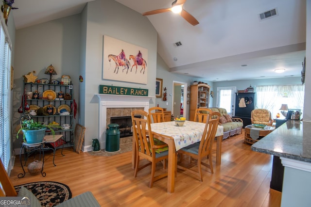 1042 Moss Creek Cir, Statesboro, GA 30461 - dining room with ceiling fan, lofted ceiling, light wood finished floors, and a tiled fireplace