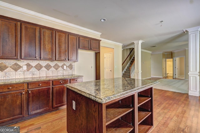 1132 Hargrove Ct, Locust Grove, GA 30248 - kitchen with decorative columns, ornamental molding, light wood finished floors, tasteful backsplash, and stone countertops