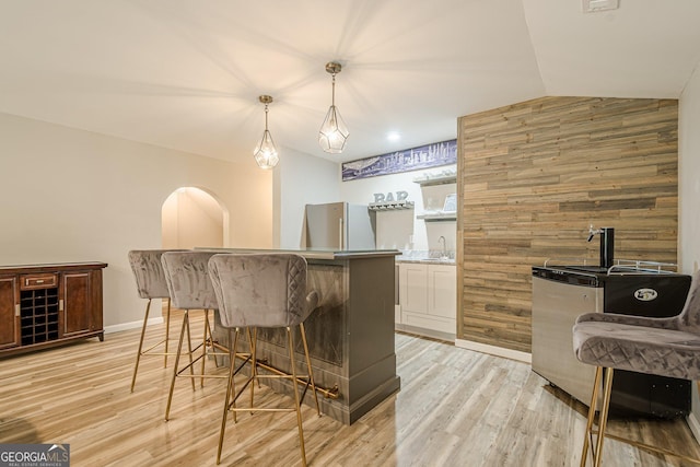 4096 Vinings Mill Trl SE, Smyrna, GA 30080 - indoor wet bar with freestanding refrigerator, light wood-style floors, lofted ceiling, hanging light fixtures, and wooden walls