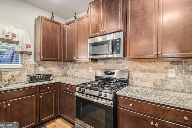 210 Kestrel Cir, Covington, GA 30014 - kitchen featuring appliances with stainless steel finishes, light stone counters, decorative backsplash, and dark brown cabinets