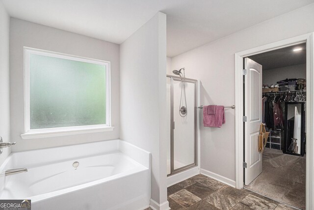 210 Kestrel Cir, Covington, GA 30014 - bathroom featuring a garden tub, a walk in closet, a shower stall, and stone finish flooring