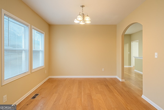 2650 Batavia St, East Point, GA 30344 - empty room featuring light wood finished floors, a chandelier, baseboards, and arched walkways