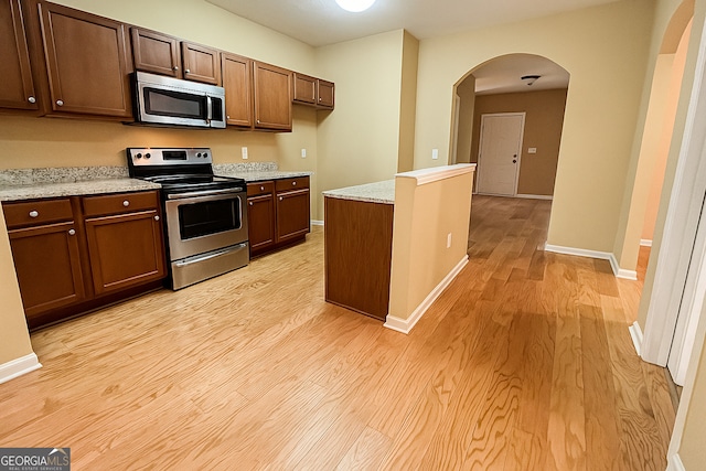 2650 Batavia St, East Point, GA 30344 - kitchen featuring stainless steel appliances, arched walkways, light wood-type flooring, and baseboards