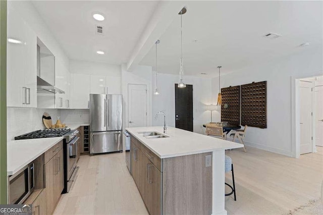 775 Juniper St NE Unit 111, Atlanta, GA 30308 - kitchen with appliances with stainless steel finishes, modern cabinets, white cabinetry, a kitchen island with sink, and light wood-style flooring