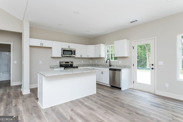 232 Stephens Rd, Cedartown, GA 30125 - kitchen with appliances with stainless steel finishes, white cabinets, a kitchen island, light wood-type flooring, and light stone countertops