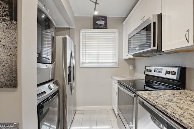 251 Shakespeare Dr Unit 332, Clayton, GA 30525 - kitchen featuring appliances with stainless steel finishes, stacked washer and clothes dryer, white cabinets, and light stone countertops