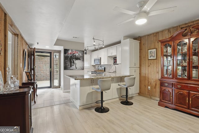 251 Shakespeare Dr Unit 332, Clayton, GA 30525 - kitchen featuring stainless steel microwave, a peninsula, wooden walls, white cabinetry, and light stone countertops
