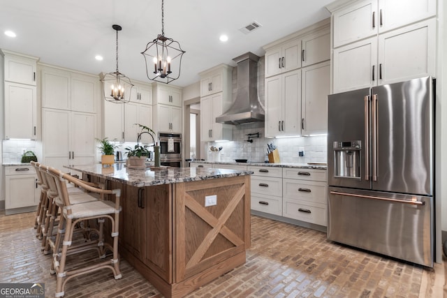 5700 Goolsby Rd, Monticello, GA 31064 - kitchen featuring appliances with stainless steel finishes, wall chimney range hood, brick flooring, a chandelier, and tasteful backsplash