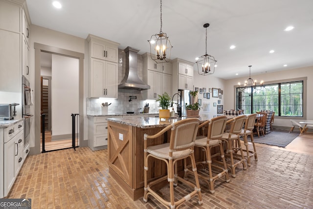 5700 Goolsby Rd, Monticello, GA 31064 - kitchen featuring wall chimney exhaust hood, a chandelier, brick floors, recessed lighting, and backsplash