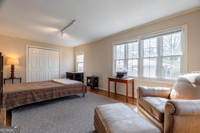 380 Best Dr, Athens, GA 30606 - bedroom featuring rail lighting, crown molding, wood finished floors, a closet, and a wood stove