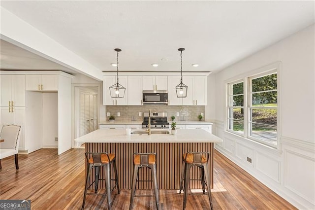 3422 Maplehurst Dr, Decatur, GA 30032 - kitchen featuring appliances with stainless steel finishes, wood finished floors, tasteful backsplash, white cabinetry, and recessed lighting