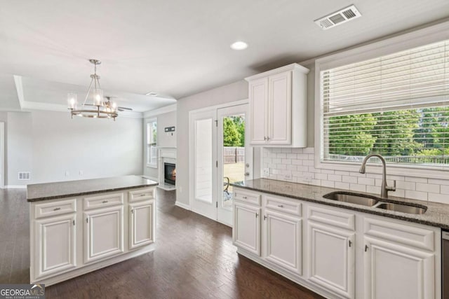 4650 Orchard View Way, Cumming, GA 30028 - kitchen featuring tasteful backsplash, a fireplace with flush hearth, white cabinets, dark wood finished floors, and a chandelier