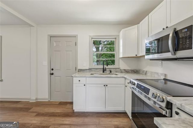 1261 Cliffwood Dr SE, Smyrna, GA 30080 - kitchen featuring appliances with stainless steel finishes, a sink, white cabinets, and wood finished floors