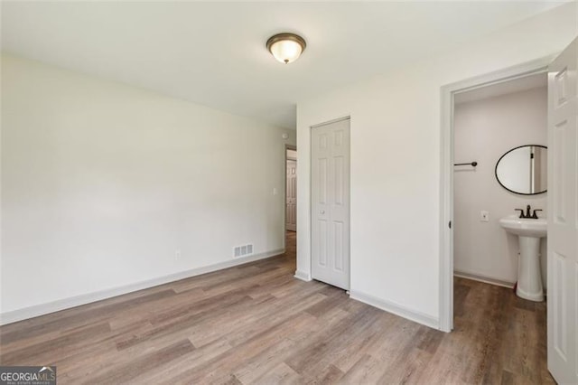 1261 Cliffwood Dr SE, Smyrna, GA 30080 - unfurnished bedroom with wood finished floors, a closet, baseboards, and a sink