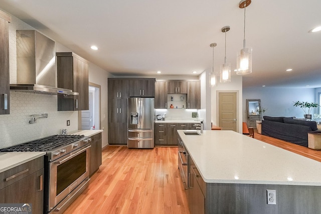 1267 Thomas Rd, Decatur, GA 30030 - kitchen with wall chimney exhaust hood, appliances with stainless steel finishes, decorative backsplash, light wood-style floors, and a sink