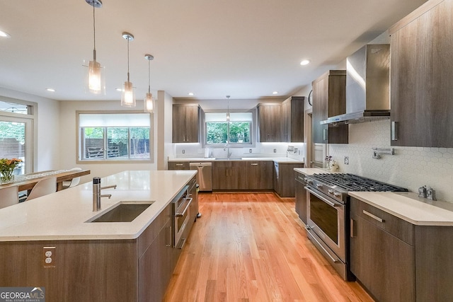 1267 Thomas Rd, Decatur, GA 30030 - kitchen with appliances with stainless steel finishes, wall chimney exhaust hood, a sink, light wood-style floors, and backsplash