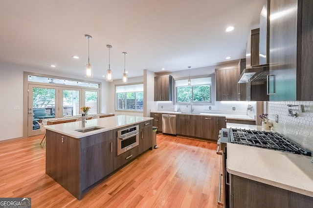 1267 Thomas Rd, Decatur, GA 30030 - kitchen with stainless steel appliances, a sink, a kitchen island, decorative backsplash, and light wood-type flooring