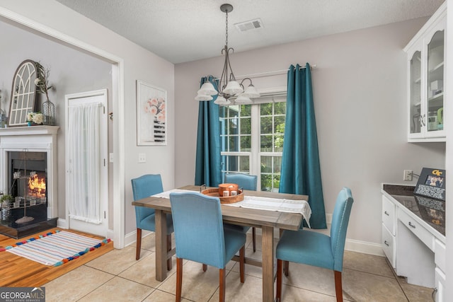 158 Sugarloaf Cir, Macon, GA 31204 - dining area with light tile patterned floors, a lit fireplace, a chandelier, baseboards, and a textured ceiling