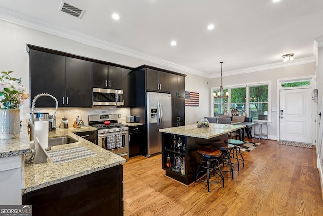 190 Marion Pl NE, Atlanta, GA 30307 - kitchen with stainless steel appliances, a sink, dark cabinetry, light wood finished floors, and crown molding