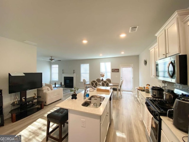 2757 Malton Way, Loganville, GA 30052 - kitchen with stainless steel microwave, gas stove, light countertops, a breakfast bar area, and a center island with sink
