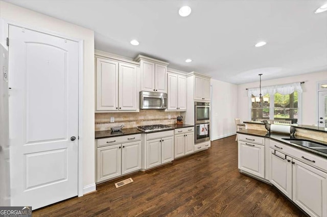 622 Rocky Creek Pt, Woodstock, GA 30188 - kitchen with stainless steel appliances, dark countertops, a chandelier, tasteful backsplash, and dark wood-style flooring