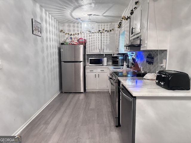 170 Graystone Cir, Macon, GA 31211 - kitchen featuring stainless steel appliances, under cabinet range hood, light countertops, white cabinetry, and light wood finished floors