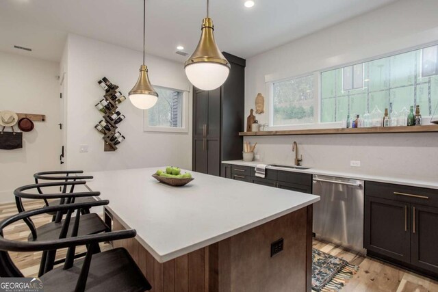 1168 Mado Loop, Chattahoochee Hills, GA 30268 - kitchen with stainless steel dishwasher, a sink, light countertops, light wood-style flooring, and a kitchen bar