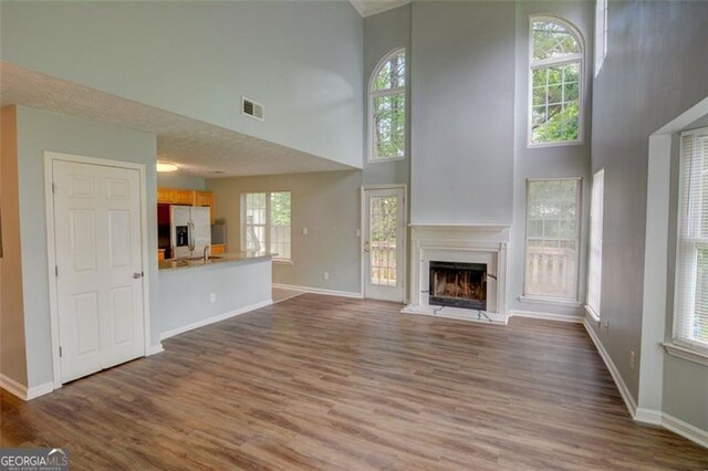 5920 Hampton Ct, College Park, GA 30349 - unfurnished living room featuring a high end fireplace, a towering ceiling, dark wood-type flooring, and baseboards