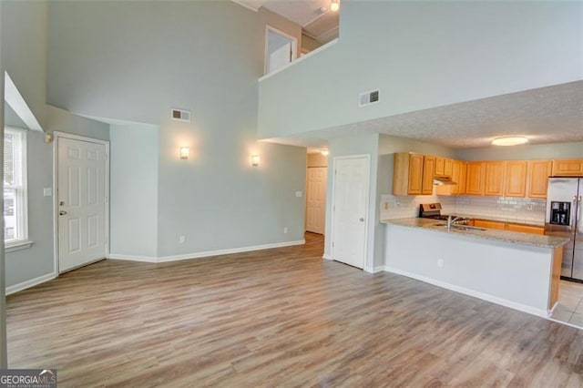 5920 Hampton Ct, College Park, GA 30349 - kitchen featuring appliances with stainless steel finishes, a high ceiling, light wood finished floors, decorative backsplash, and baseboards