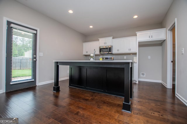 309 Dean Ct, Temple, GA 30179 - kitchen with stainless steel microwave, white cabinets, dark wood-style flooring, baseboards, and recessed lighting