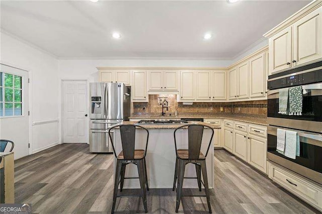 1039 Avery Creek Dr, Woodstock, GA 30188 - kitchen featuring stainless steel appliances, cream cabinets, dark wood finished floors, recessed lighting, and ornamental molding