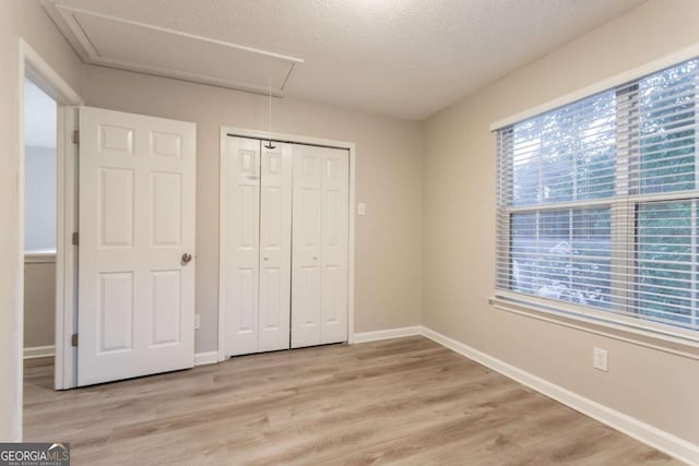 7113 Ambercrest Ct, Austell, GA 30168 - unfurnished bedroom with attic access, light wood-style flooring, a textured ceiling, and a closet