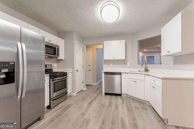 7113 Ambercrest Ct, Austell, GA 30168 - kitchen with appliances with stainless steel finishes, a textured ceiling, light wood-type flooring, and white cabinetry
