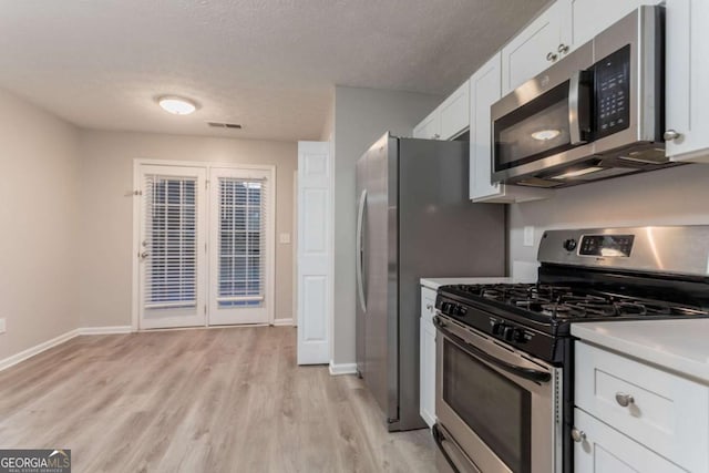 7113 Ambercrest Ct, Austell, GA 30168 - kitchen with appliances with stainless steel finishes, white cabinets, light wood-style flooring, light countertops, and a textured ceiling