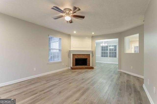 7113 Ambercrest Ct, Austell, GA 30168 - unfurnished living room featuring ceiling fan, a chandelier, light wood finished floors, recessed lighting, and a brick fireplace