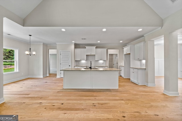 21 Oakgrove Trl, Griffin, GA 30224 - kitchen with vaulted ceiling, white cabinets, a center island with sink, light stone countertops, and decorative backsplash