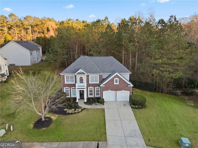 3224 Wolf Club Ln SW, Atlanta, GA 30349 - colonial house with concrete driveway, a view of trees, an attached garage, a front yard, and brick siding