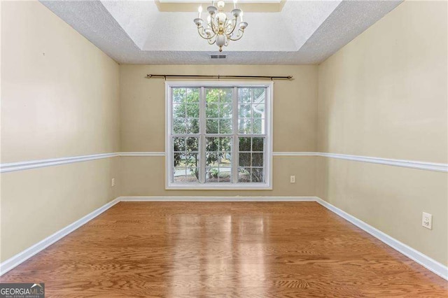 1934 Mcconnell Rd, Grayson, GA 30017 - empty room featuring wood finished floors, a chandelier, a textured ceiling, and a tray ceiling