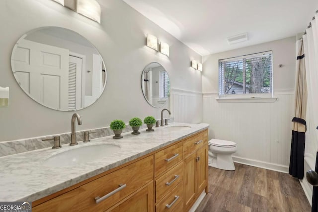 5860 Riverwood Dr, Sandy Springs, GA 30328 - full bathroom with double vanity, a wainscoted wall, plenty of natural light, wood finished floors, and toilet