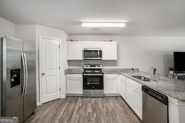 1776 Cheryl Ave, Griffin, GA 30224 - kitchen with appliances with stainless steel finishes, wood finished floors, white cabinetry, a peninsula, and light stone countertops