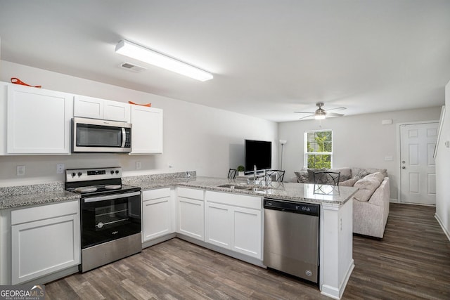 1776 Cheryl Ave, Griffin, GA 30224 - kitchen featuring appliances with stainless steel finishes, a peninsula, open floor plan, dark wood-style floors, and white cabinets