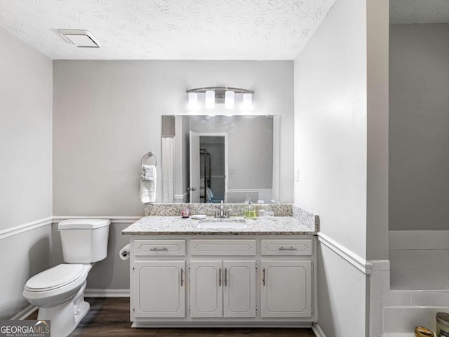 30 Court S, Ellenwood, GA 30294 - full bathroom featuring toilet, vanity, a textured ceiling, a bath, and baseboards