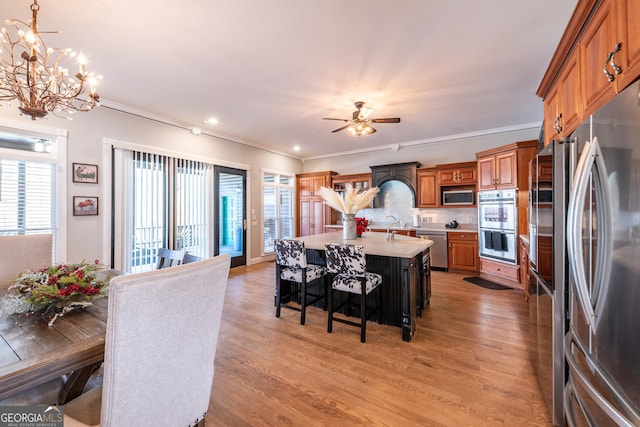 33 T J Mote Rd, Dahlonega, GA 30533 - kitchen featuring appliances with stainless steel finishes, light countertops, light wood-style flooring, brown cabinets, and ornamental molding