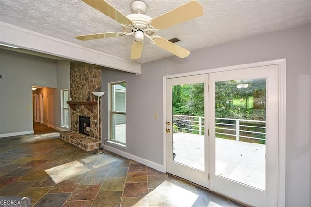 4766 Jamerson Forest Cir, Marietta, GA 30066 - doorway with stone tile floors, a textured ceiling, a fireplace, and ceiling fan