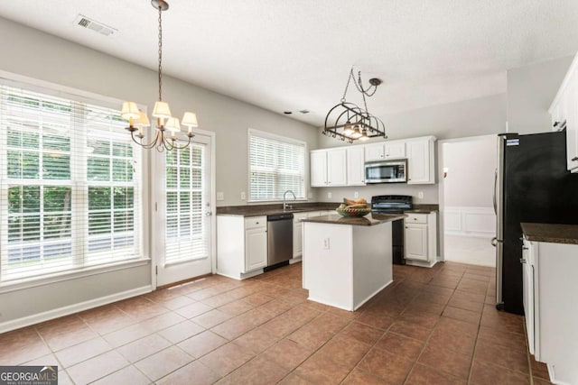 144 Nocatee Trl, Woodstock, GA 30188 - kitchen featuring appliances with stainless steel finishes, dark countertops, a chandelier, dark tile patterned floors, and a kitchen island