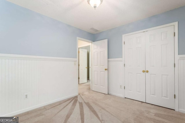 144 Nocatee Trl, Woodstock, GA 30188 - unfurnished bedroom featuring a closet, carpet, a textured ceiling, and wainscoting