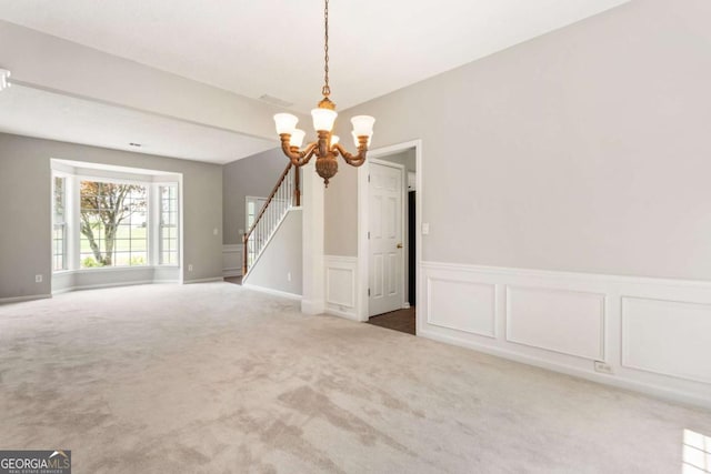 144 Nocatee Trl, Woodstock, GA 30188 - carpeted empty room with a chandelier, wainscoting, stairs, and a decorative wall