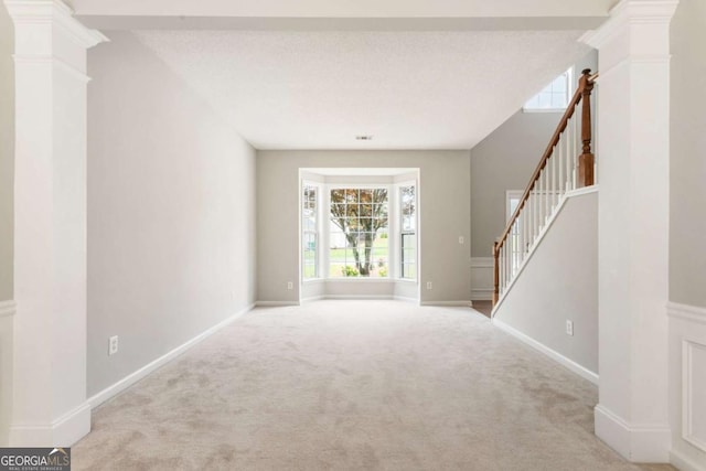 144 Nocatee Trl, Woodstock, GA 30188 - unfurnished living room featuring carpet flooring, stairs, and ornate columns