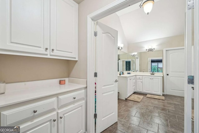 1979 Alcovy Shoals Blf, Lawrenceville, GA 30045 - kitchen featuring white cabinetry, vaulted ceiling, light countertops, and stone finish floors