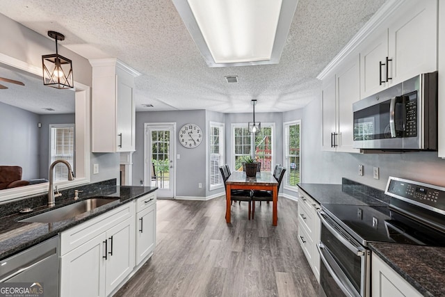 1415 Langdon Park Ct, Winder, GA 30680 - kitchen featuring appliances with stainless steel finishes, a textured ceiling, wood finished floors, white cabinets, and dark stone countertops